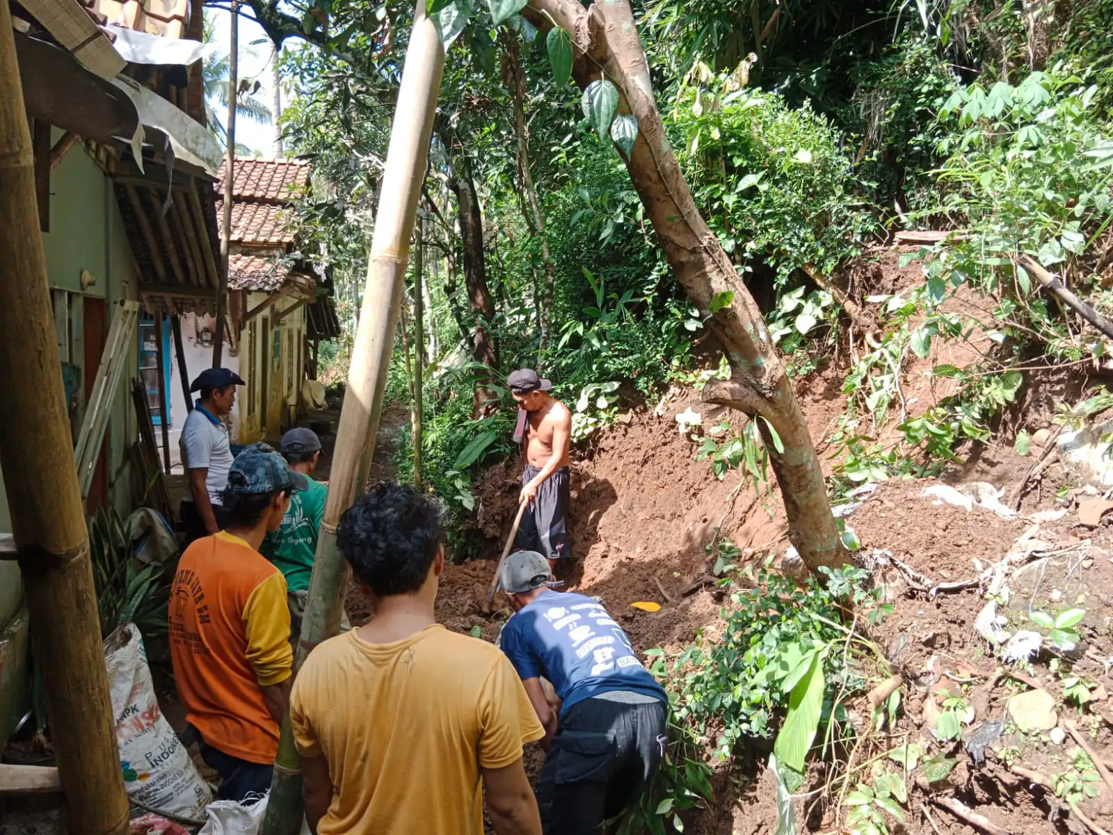 Gotong Royong, Bhabinkamtibmas Polsek Cilongok Polresta Banyumas Evakuasi Material Longsor Di Halaman Rumah Warga